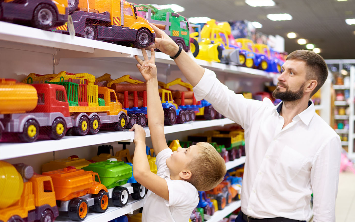 Toy store associate helping young customer choose a toy from the shelf