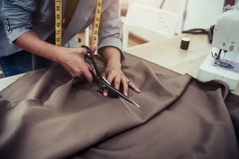 Fabric being measured and cut at cutting table in fabric store