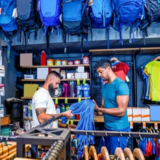 Sporting goods store employee assisting customer with athletic gear