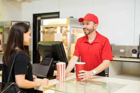 Concession staff member taking customer order on tablet in stadium concourse during event