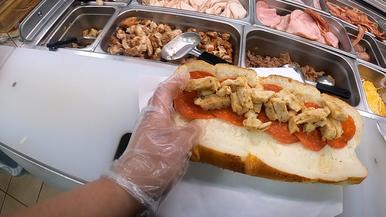 Sandwich shop staff member taking customer order on tablet in the line at lunch rush